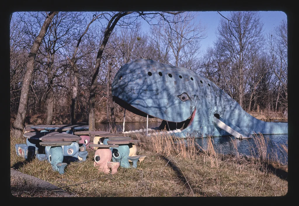 A 1995 view of the Blue Whale behind tall grass, with round picnic tables in the foreground.